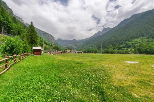 a green field with a fence and mountains in the background at La chambre d'Emilie - romantic room in Valtournenche