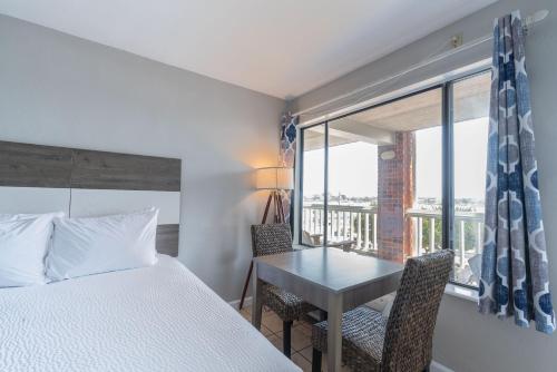 奥克拉科克Anchorage Inn & Marina的一间卧室，里面有一张床、一张桌子和一扇窗户