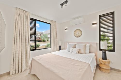 a white bedroom with a large bed and a large window at Blue Bay Curaçao Golf & Beach Resort in Willemstad