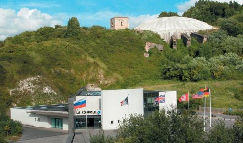 a building with flags in front of a hill at La ferme Le Clos de la Becque in Muncq-Nieurlet