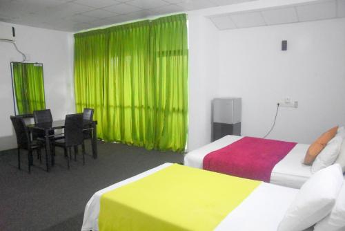 a hotel room with two beds and a table and chairs at Hotel Romi Gampaha in Gampaha