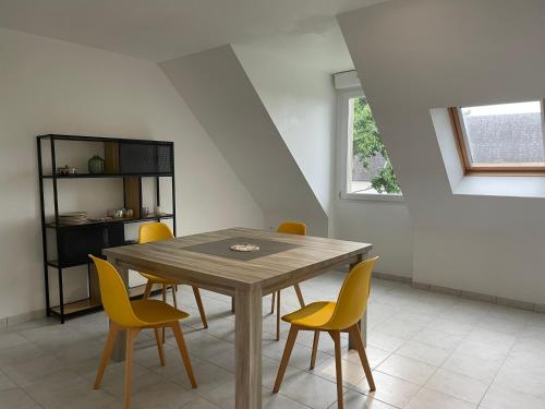 une salle à manger avec une table en bois et des chaises jaunes dans l'établissement Petit loft, à Pleyben