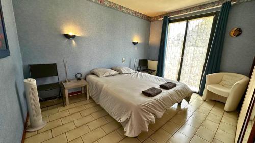 une chambre avec un lit, une chaise et une fenêtre dans l'établissement La Villa du Claus avec Jacuzzi, Jardin et BBQ, à Saint-Mathieu-de-Tréviers