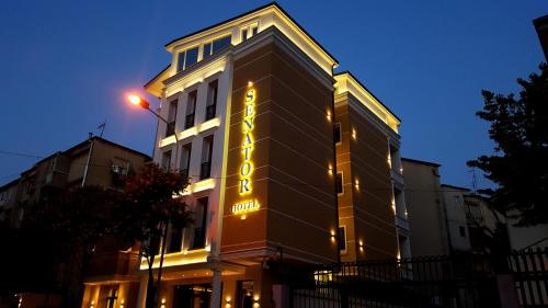 ein Gebäude mit einem Neonschild auf der Seite in der Unterkunft Senator Hotel in Tirana