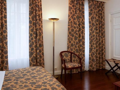 a bedroom with a bed and a chair and a window at Hotel Du Parc - Mulhouse Centre in Mulhouse