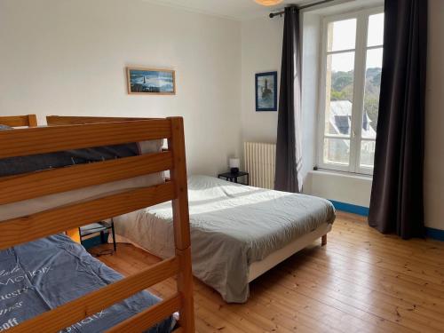 une chambre avec un lit superposé et une fenêtre dans l'établissement Maison familiale vue mer - jardin arboré, à Douarnenez