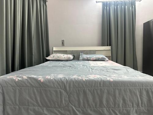 a bedroom with a large bed with green curtains at Woodside Haven Luxury GF in Auroville