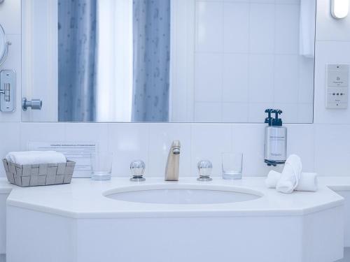 a bathroom sink with two glasses and a mirror at Hotel Du Parc - Mulhouse Centre in Mulhouse