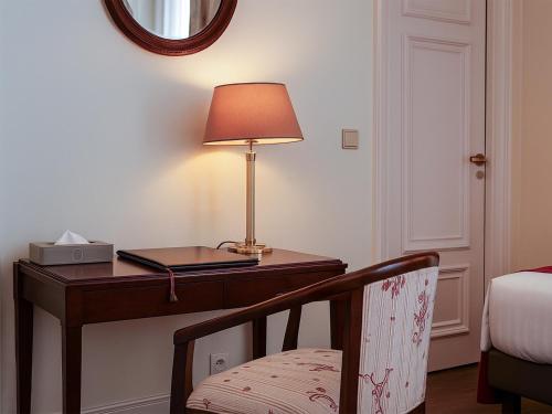 a bedroom with a desk with a lamp and a chair at Hotel Du Parc - Mulhouse Centre in Mulhouse