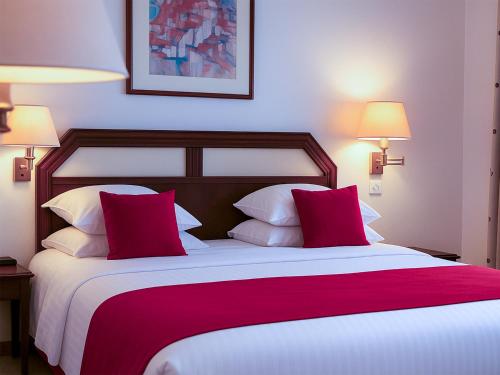a bedroom with a large bed with red and white pillows at Hotel Du Parc - Mulhouse Centre in Mulhouse