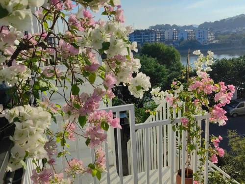 a white fence with pink and white flowers on it at Seven Love Letters Zen Tea and Flower Bed and Breakfast in Huangshan