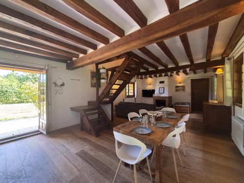 a dining room with a wooden table and white chairs at Maison au calme à la campagne in Les Bottereaux