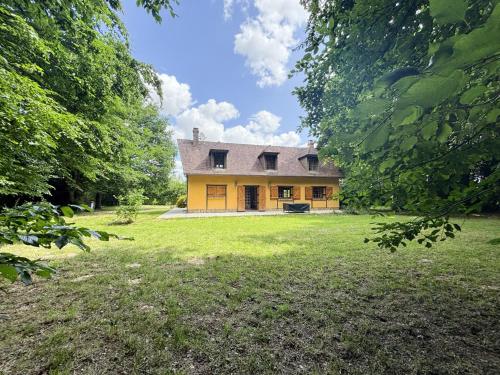 a large yellow house in a field with trees at Maison au calme à la campagne in Les Bottereaux