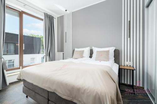a bedroom with a large bed and a large window at Your Holidays Golden Tulip in Międzyzdroje