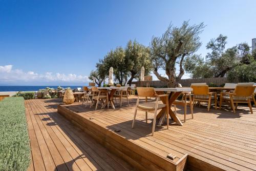 a wooden deck with tables and chairs and the ocean at Alissachni SeaSide Hotel in Derveni