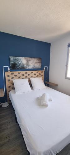 - une chambre avec un grand lit blanc et un mur bleu dans l'établissement 50m DE LA PLAGE, CLIM, JOLI APPARTEMENT 6p, SECTEUR GRANDE PLAGE, au Barcarès