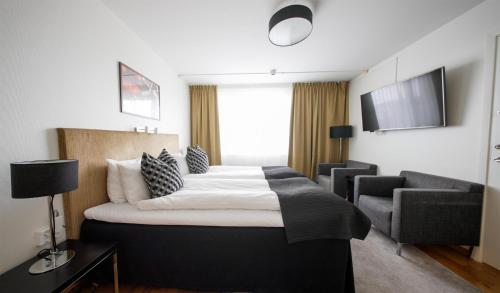 a hotel room with a bed and a chair at Best Western Plus Grand Hotel Elektra in Ludvika