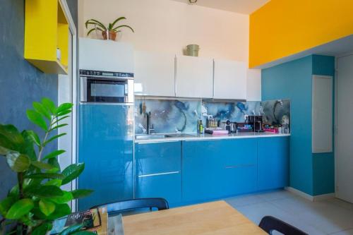 une cuisine bleue avec des placards blancs et une table dans l'établissement Appartement Marseille Malmousque et Mer, à Marseille