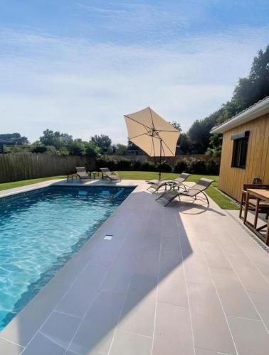 une piscine avec un parasol, une table et des chaises dans l'établissement maison Lège cozy, à Lège-Cap-Ferret