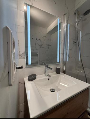 une salle de bain blanche avec un lavabo et un miroir dans l'établissement Appartement Montagne Randonnées centre la Foux d'Allos - Eté & Hiver, à Allos