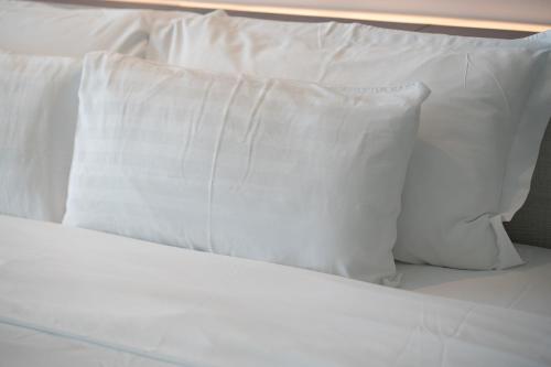a pile of white pillows on a bed at Welcome Parkhotel Bochum in Bochum