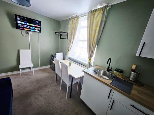 a kitchen with a sink and a table with chairs at OceanNest-3 Bedroom Apartment free parking, EV 22kW in Portsmouth