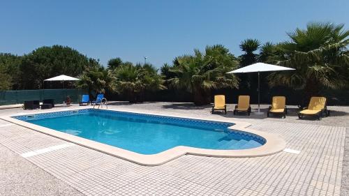 a swimming pool with chairs and umbrellas on a patio at Catshouse in Carqueja