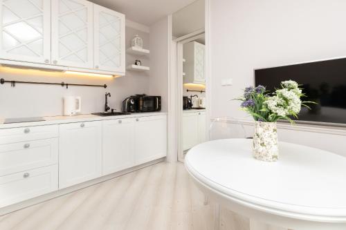 biała kuchnia z wazonem kwiatów na stole w obiekcie Apartments Tartaczna 2 - Gdansk Old Town by Noclegi Renters w Gdańsku