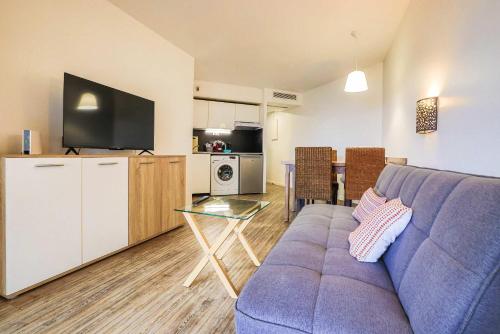 Il comprend un salon avec un canapé violet et une cuisine. dans l'établissement Le Cannes Beach 199C - lumineux vue mer - piscine, à Cannes