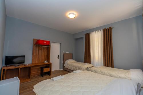 a room with two beds and a television in it at Gjuhadoli Hotel 2 in Shkodër