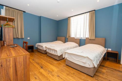two beds in a room with blue walls and wooden floors at Gjuhadoli Hotel 2 in Shkodër
