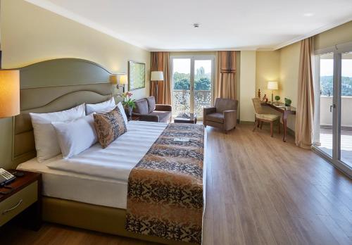 Ramada Resort Kazdağlari Thermal & Spa في غوري: غرفة الفندق بسرير كبير ومكتب