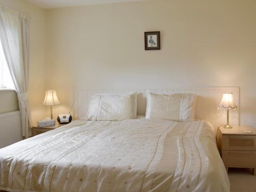 a bedroom with a large white bed with two lamps at Dormers in Leiston