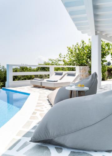 a patio with pillows and a table next to a pool at Oniro Skiathos in Skiathos Town