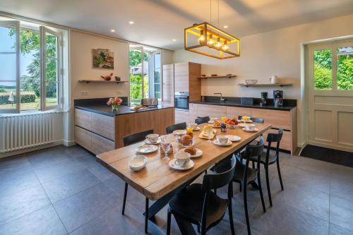 a large kitchen with a wooden table and chairs at Le Pasty - Piscine - Tennis - Puy du Fou in Saint-Aubin-de-Luigné