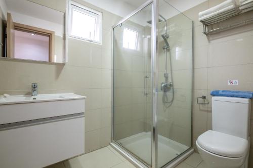 a bathroom with a shower and a toilet and a sink at Bellini Hotel in Ayia Napa