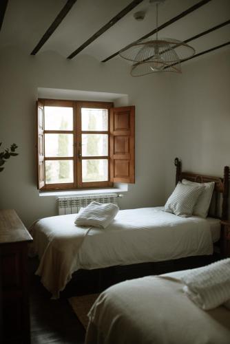 two beds in a room with a window at Hotel Palacio de Caranceja in Reocín