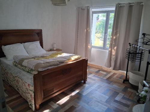 a bedroom with a wooden bed with a window at les noisetiers de verinas in Rochechouart