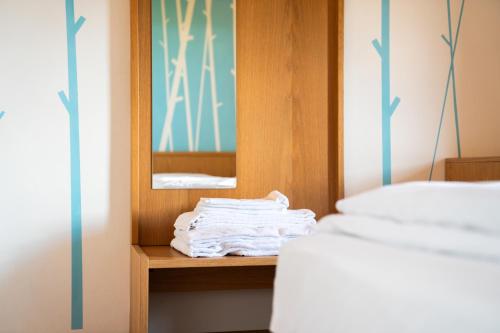 a pile of towels sitting on a shelf next to a bed at Enrosadira in Predaia