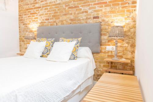 sypialnia z łóżkiem i ścianą z cegły w obiekcie Alohamundi Ardilla w Sewilli