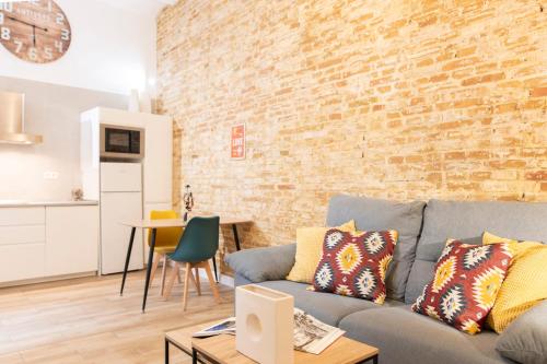 salon z kanapą i ceglaną ścianą w obiekcie Alohamundi Ardilla w Sewilli