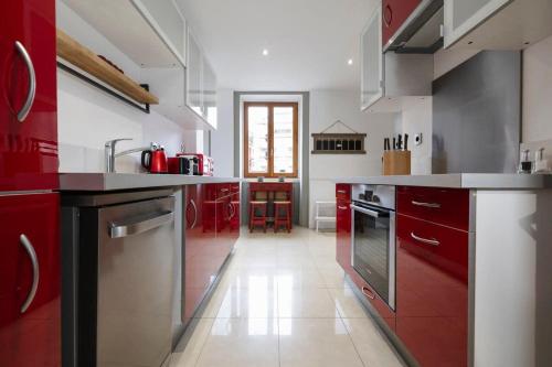 une grande cuisine avec des placards rouges et des appareils électroménagers dans l'établissement Central Chamonix - Quiet & Parking 5px Apartment, à Chamonix-Mont-Blanc