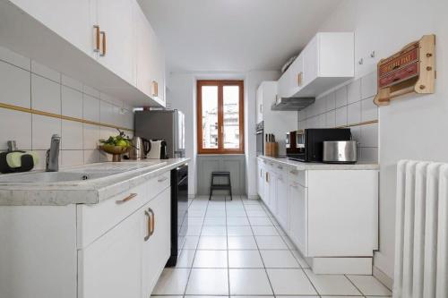 Il comprend une cuisine avec des placards blancs et du carrelage blanc. dans l'établissement Central Chamonix - Quiet & Parking 6 px Apartment, à Chamonix-Mont-Blanc