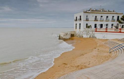 a building on the beach next to the ocean at Chipiona Center in Chipiona