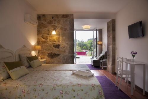 a bedroom with a large bed with a stone wall at Quinta do Cerqueiral in Arcos de Valdevez