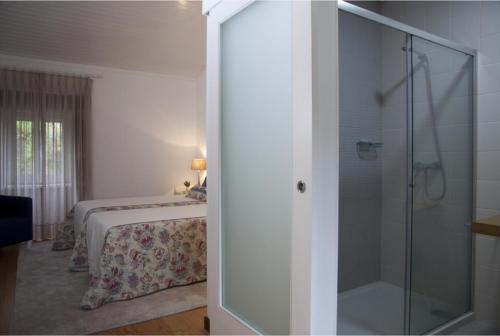 アルコス・デ・ヴァルデヴェスにあるQuinta do Cerqueiralのベッドとガラスのシャワーを備えた寝室