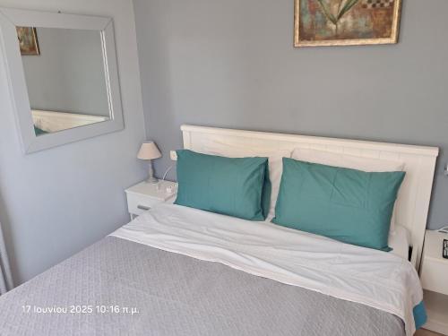a bedroom with a bed with blue pillows and a mirror at Top floor on villa, 3' from center, by the sea! Host is Efi Kwsta in Preveza