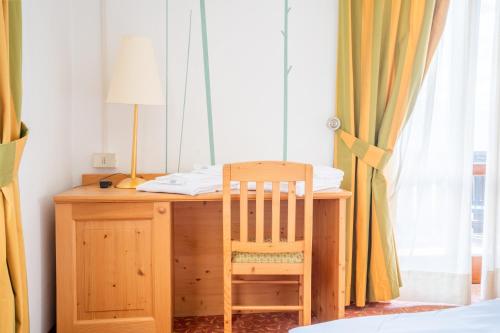 a wooden desk with a chair next to a window at Enrosadira in Predaia