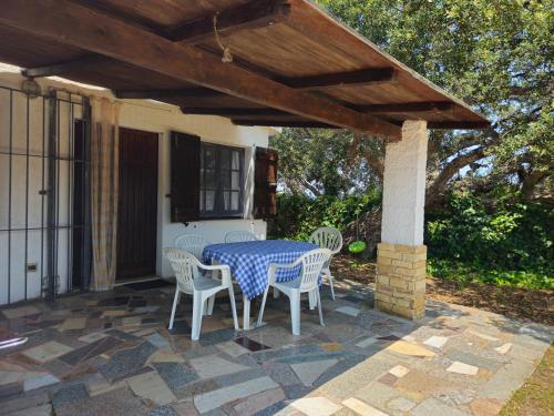 a patio with a table and chairs under a wooden roof at Country house La grande quercia in SantʼAntìoco