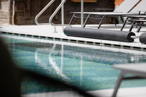 a swimming pool with chairs and a table at Neueröffnung ELVA PREMIUM APARTMENT HOTEL inklusive Sommerpass STUBAI SUPER CARD in Neustift im Stubaital